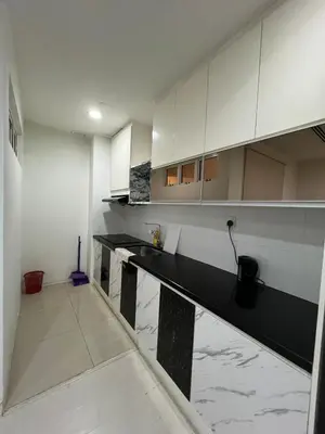 a kitchen with white cabinets and black counter tops at Great Value 2-Bedroom KLCC Unit in Kuala Lumpur