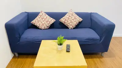 a blue couch with a remote control on a coffee table at Mercu Summer Suites near KLCC in Kuala Lumpur
