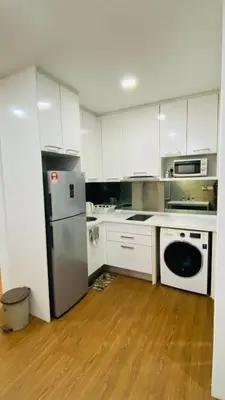 a kitchen with white cabinets and a stainless steel refrigerator at Mercu Summer Suites near KLCC in Kuala Lumpur