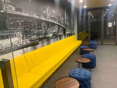 a yellow couch in a restaurant with tables and stools at Mini studio Neu suites KLCC in Kuala Lumpur