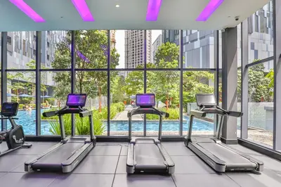 a gym with a row of treadmills in a building at Star Deluxe Suites KLCC by WSD in Kuala Lumpur