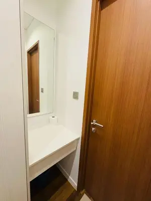 a bathroom with a white sink and a wooden door at URBAN COZY HOME at SkySuites Near KLCC Complimentary Breakfast in Kuala Lumpur