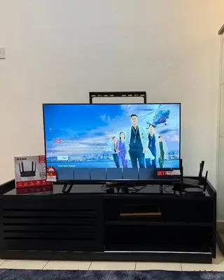 a flat screen tv sitting on top of a black entertainment center at URBAN COZY HOME at SkySuites Near KLCC Complimentary Breakfast in Kuala Lumpur