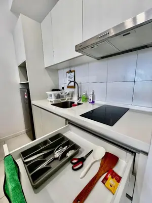 a kitchen with white cabinets and a sink and scissors at Chamber KL Residence by Moon Orchid in Kuala Lumpur