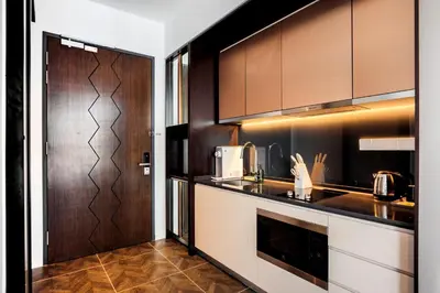 a kitchen with brown cabinets and a counter top at Scarletz Suites KLCC by TaheeenS in Kuala Lumpur