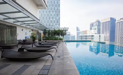 a hotel swimming pool with chairs and buildings at COZY SUPER KING BED STUDIO walking to PETRONAS KLCC by Zen Glo in Kuala Lumpur