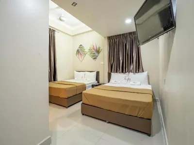 a hotel room with two beds and a flat screen tv at AGE Hotel in Kuala Lumpur
