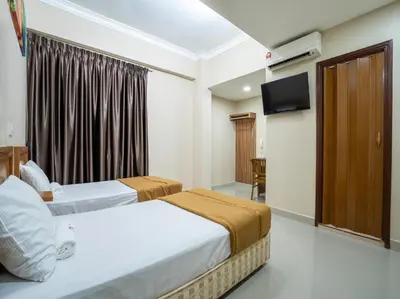 a hotel room with two beds and a television at AGE Hotel in Kuala Lumpur