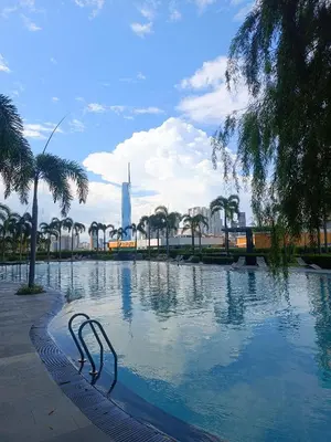 a swimming pool with palm trees and a building in the background at Trion Residence Kuala Lumpur by Azure in Kuala Lumpur