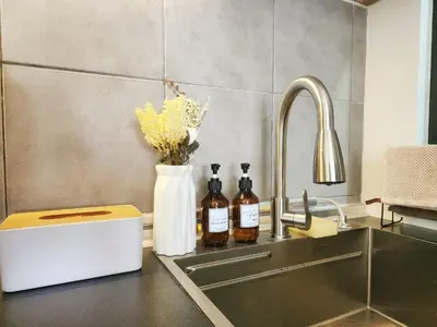 a kitchen counter with a sink with bottles on it at Family Suite M Vertica Sunway Velocity Ikea KL MRT in Kuala Lumpur