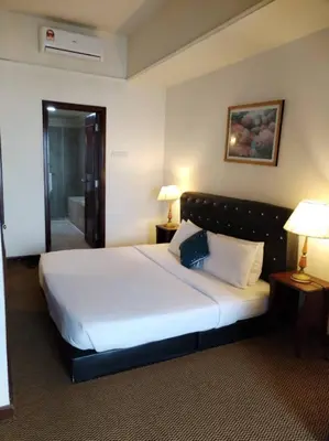 a bedroom with a large white bed with two lamps at KL Marigold Apartment At Times Square in Kuala Lumpur