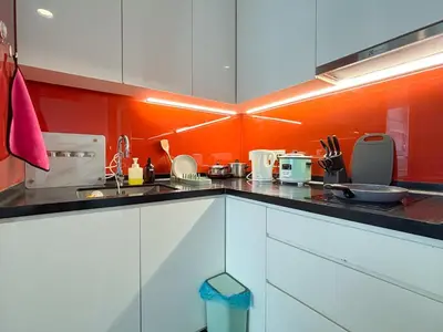 a kitchen with white cabinets and an orange wall at Arcoris Mont Kiara FaceHome in Kuala Lumpur