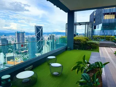 a balcony with green grass and stools on a building at Star Suites KLCC by flixses in Kuala Lumpur