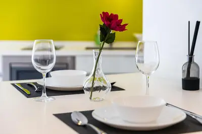 a table with two wine glasses and a red flower in a vase at The Signature Residence at Sri Hartamas - 2 pax in Kuala Lumpur
