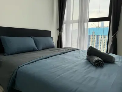 a bed with a blue blanket and a window at Trion KL By HomeTaric Suite in Kuala Lumpur