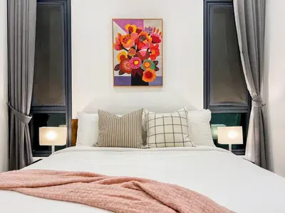 a bedroom with a white bed and a painting of flowers at Lucentia Apartments in Kuala Lumpur