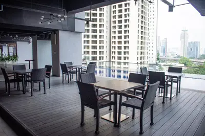 a restaurant with tables and chairs on a balcony at MyHabitat Residences in Kuala Lumpur