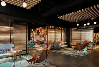 a lobby with chairs and tables and books at Moxy Kuala Lumpur Chinatown in Kuala Lumpur