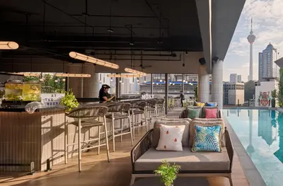 a bar on the rooftop of a building with a pool at Moxy Kuala Lumpur Chinatown in Kuala Lumpur