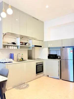 a kitchen with white cabinets and a stainless steel refrigerator at Stylish Apartment at Lucentia residence BBCC Lalaport in Kuala Lumpur