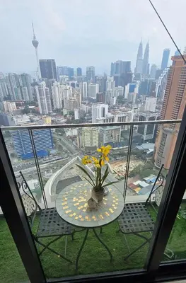 a table with a vase with flowers on a balcony at The BirdsEye View facing KLCC with Gorgeous pools in Kuala Lumpur