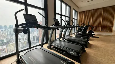 a row of treadmills in a gym with windows at The BirdsEye View facing KLCC with Gorgeous pools in Kuala Lumpur