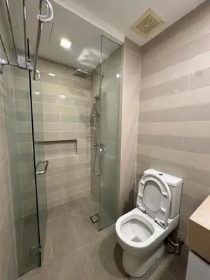 a bathroom with a toilet and a glass shower at 1 Bukit Ceylon Kuala Lumpur in Kuala Lumpur