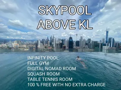 a man swimming in the water with a city in the background at Infinity Skypool hostel in Kuala Lumpur