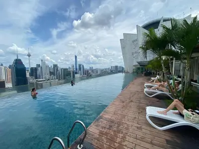 a pool on the roof of a building with people sitting in chairs at Infinity Skypool Retreat hostel in Kuala Lumpur