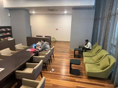 two people sitting at tables and chairs in a room at KL Infinity Luxury Skypool hostel in Kuala Lumpur
