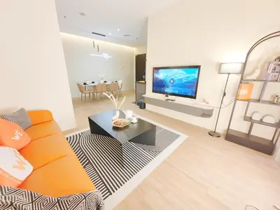 a living room with an orange couch and a tv at Weekly Monthly Stay - Bangsar Trade Centre Aspire in Kuala Lumpur