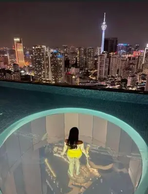 a woman standing in a pool with a view of a city at Lucentia Residences by Luxe Suites in Bukit Bintang KLCC! in Kuala Lumpur