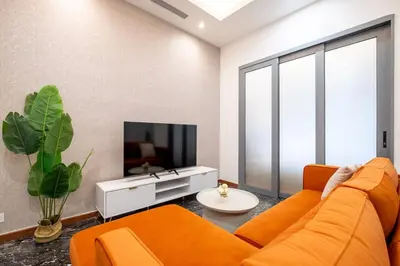 a living room with an orange couch and a tv at Le Luxe de KL 2BR with Bath Tub 10 min to KLCC in Kuala Lumpur