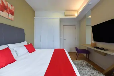 a bedroom with a bed with red pillows and a tv at Sunday Hotel Near Petronas Twin Tower Formerly Suasana Suites in Kuala Lumpur