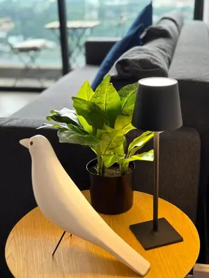 a table with a bird and a lamp and a plant at The Establishment Bangsar #2222 by Ouki in Kuala Lumpur