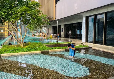 a woman standing in a fountain in front of a building at Axon Residences KLCC - Premium Suites in Kuala Lumpur
