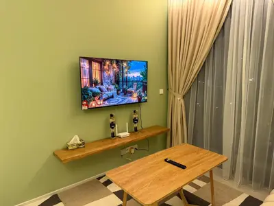 a living room with a table and a television on the wall at Cozy Urban Retreat in the Heart of the Bangsar in Kuala Lumpur