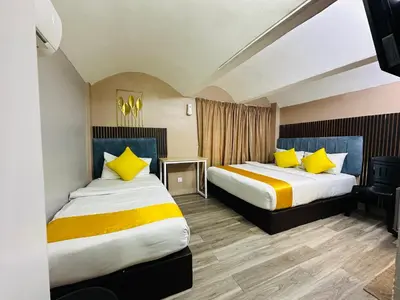 a hotel room with two beds with yellow pillows at SS Grey Hotel kL in Kuala Lumpur