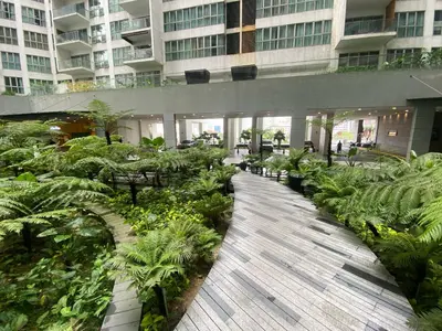 a walkway in a building with plants and tables at Skyfloat Infinity Hostel in Kuala Lumpur