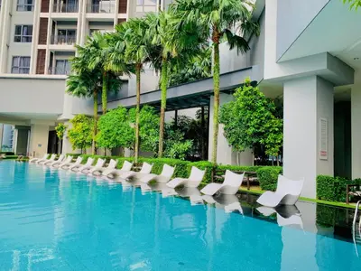 a hotel swimming pool with white chairs and palm trees at The Mews Suites KLCC By Luna in Kuala Lumpur