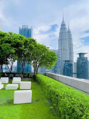 a park with white benches and a city skyline at The Mews Suites KLCC By Luna in Kuala Lumpur