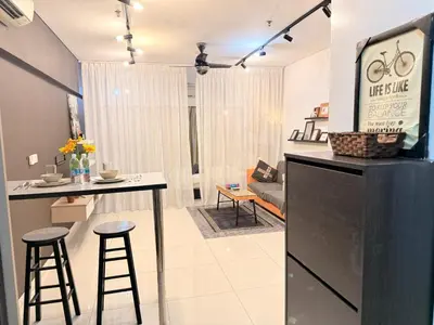 a kitchen and living room with a counter and stools at Mercu Summer Suites KLCC By Suite Apartment in Kuala Lumpur