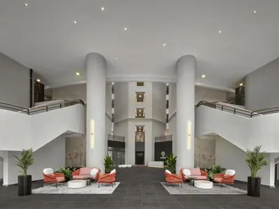 a large lobby with orange chairs and a building at The Atrium at Jalan Ampang by OKBnB - Classy Executive Family Suite 3Bedroom with Balcony , nearby KLCC in Kuala Lumpur