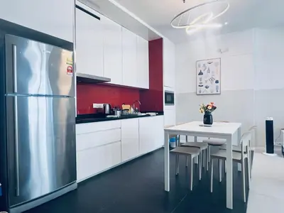a white kitchen with a table and a refrigerator at Arcoris SOHO by Cj in Kuala Lumpur
