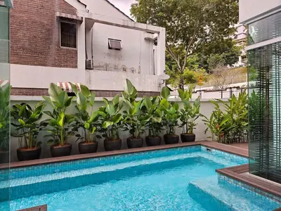 a swimming pool with potted plants next to a building at Villa Homescape, Mont Kiara in Kuala Lumpur