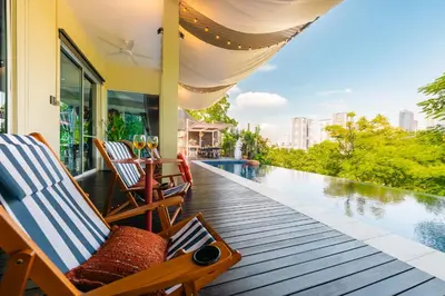 a deck with chairs and a table next to a swimming pool at Flame of the Forest Retreat 38Pax 8R7B Pool Villa Kuala Lumpur in Kuala Lumpur