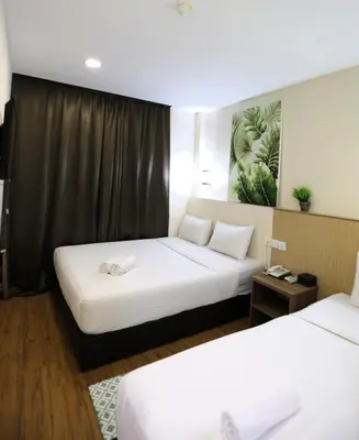 a hotel room with two beds and a table at Xpeed Holiday Hotel in Kuala Lumpur