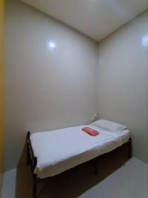 a small bed in a room with white walls at The Ohana Suite in Kuala Lumpur