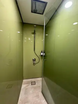 a bathroom with a shower with green walls at Modern Condo Next To Petronas Towers in Kuala Lumpur