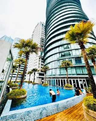 a pool with palm trees in front of a building at Vortex Premium Apartment klcc in Kuala Lumpur